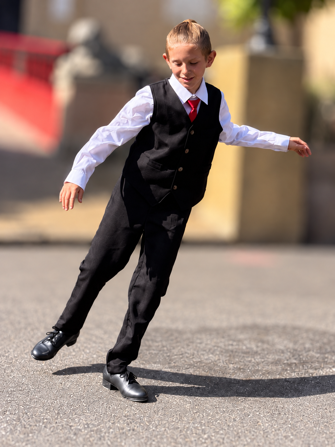 Christophe dancing outdoors in a shirt, waistcoat and tap shoes, with a softly blurred background